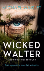 Image of a menacing looking man staring through plam trees.